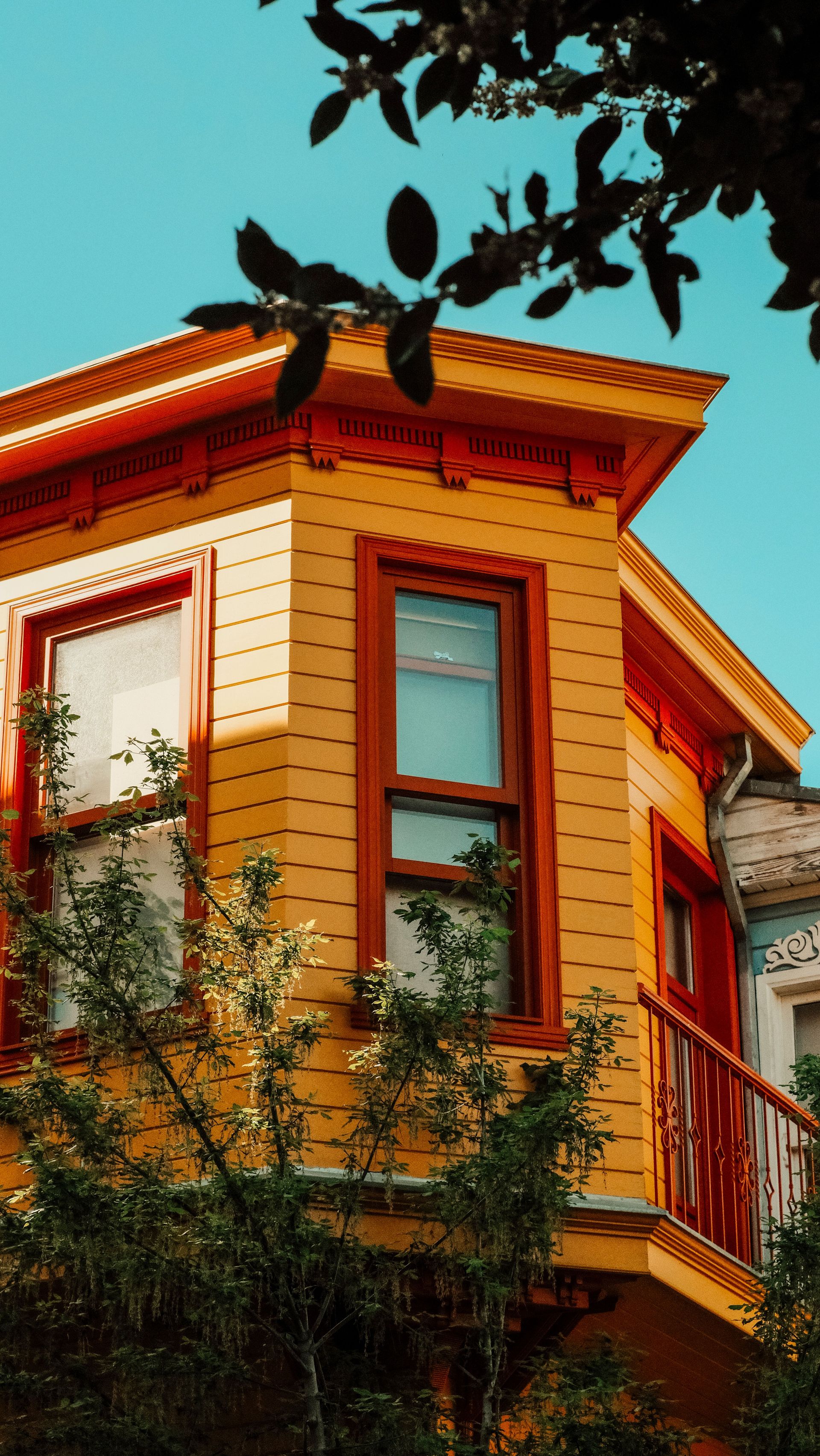 Colorful residential building facade with vibrant yellow paint and balcony, set against a clear sky in İstanbul.